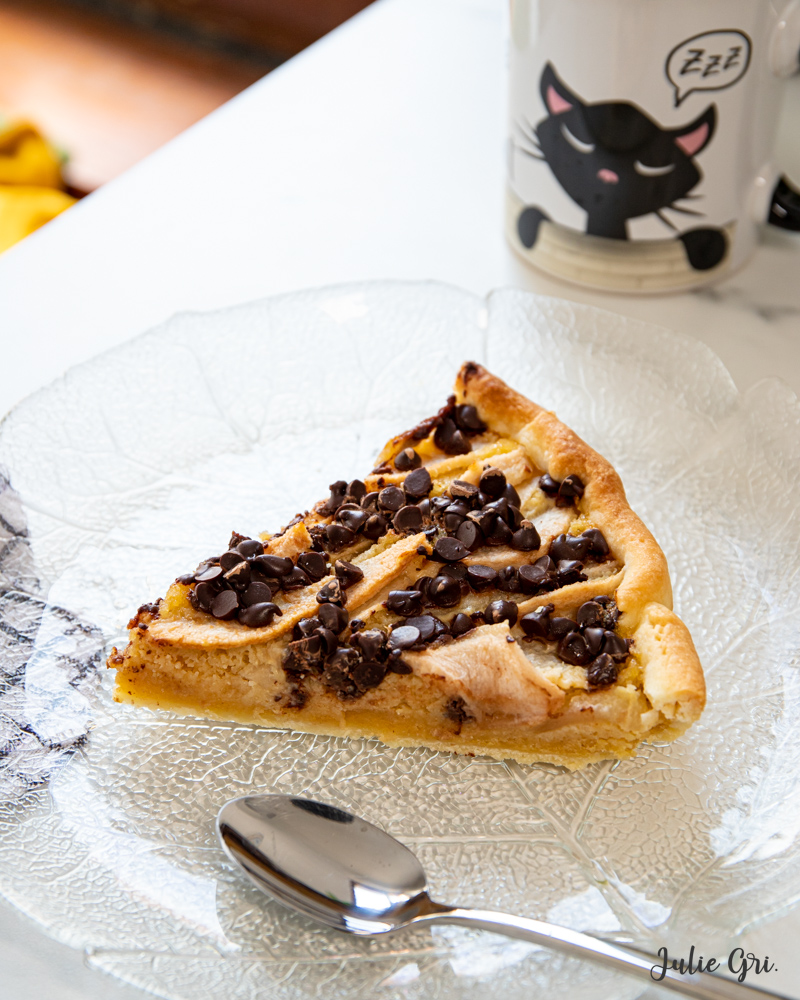 part de tarte aux poires et chocolat présentée sur une assiette en verre